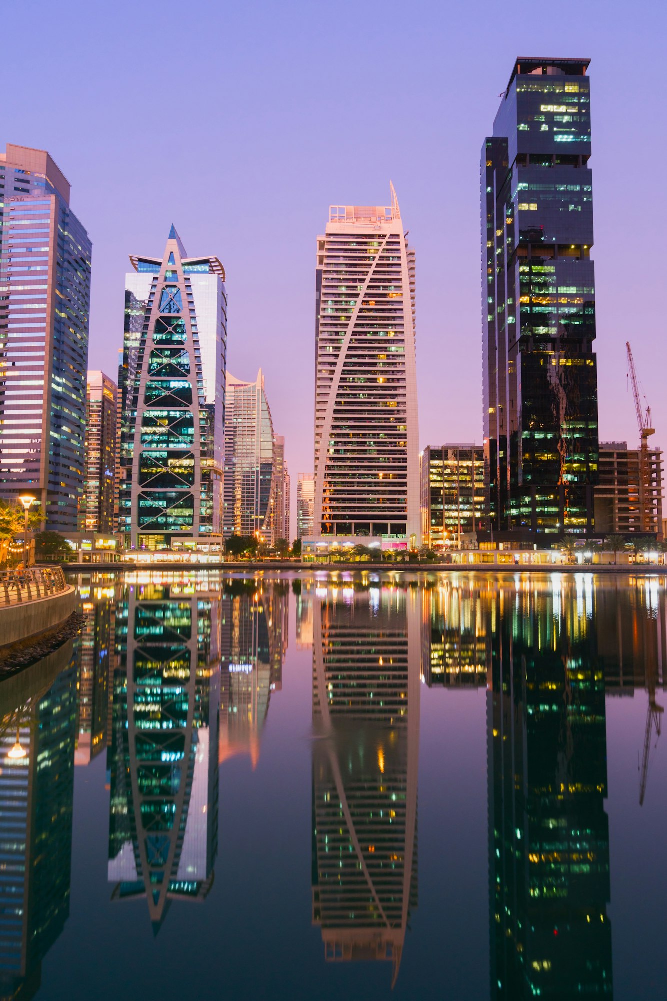 Modern skyscrapers and water pier of Dubai Marina at sunset and blue hour.